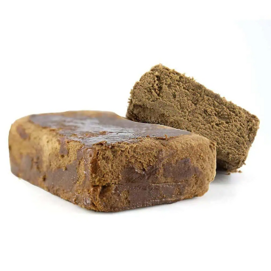 Nepal Cream hash blok med mørk yderside og lys brun indre struktur vist i close-up fra sidevinkel på hvid baggrund.